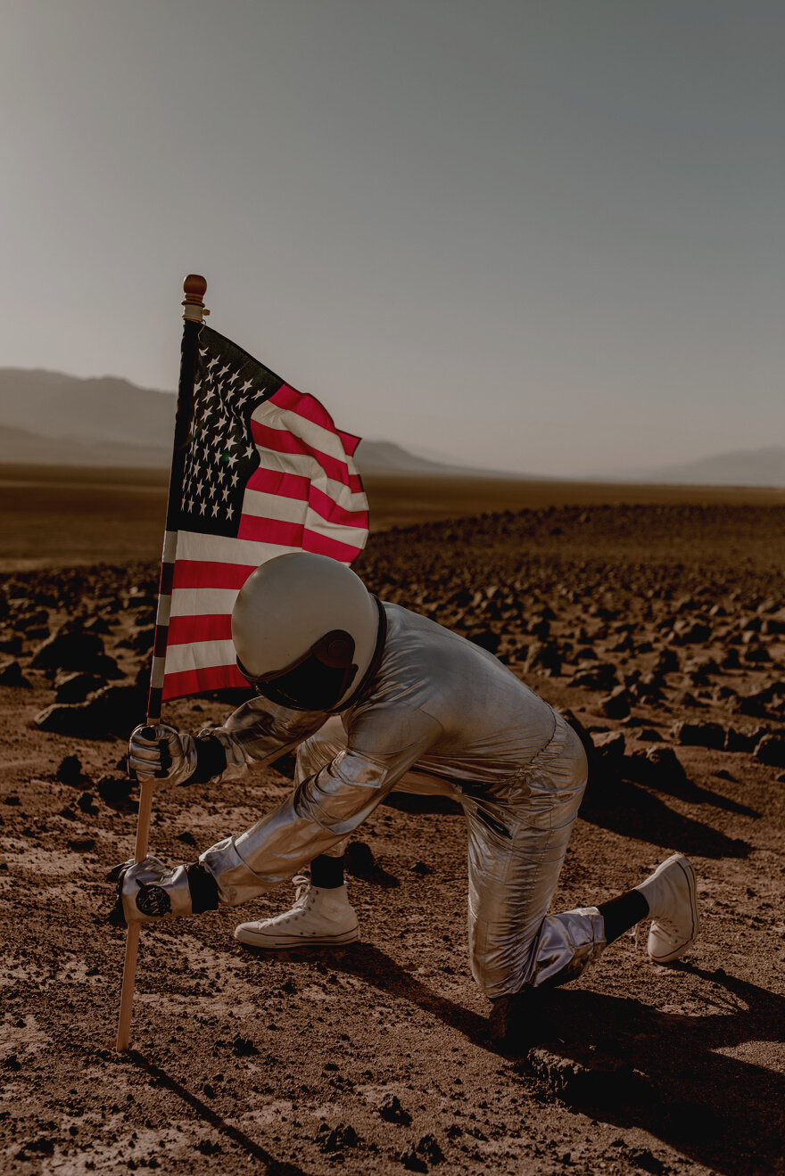 An Astronaut Sticking an American Flag in the Ground